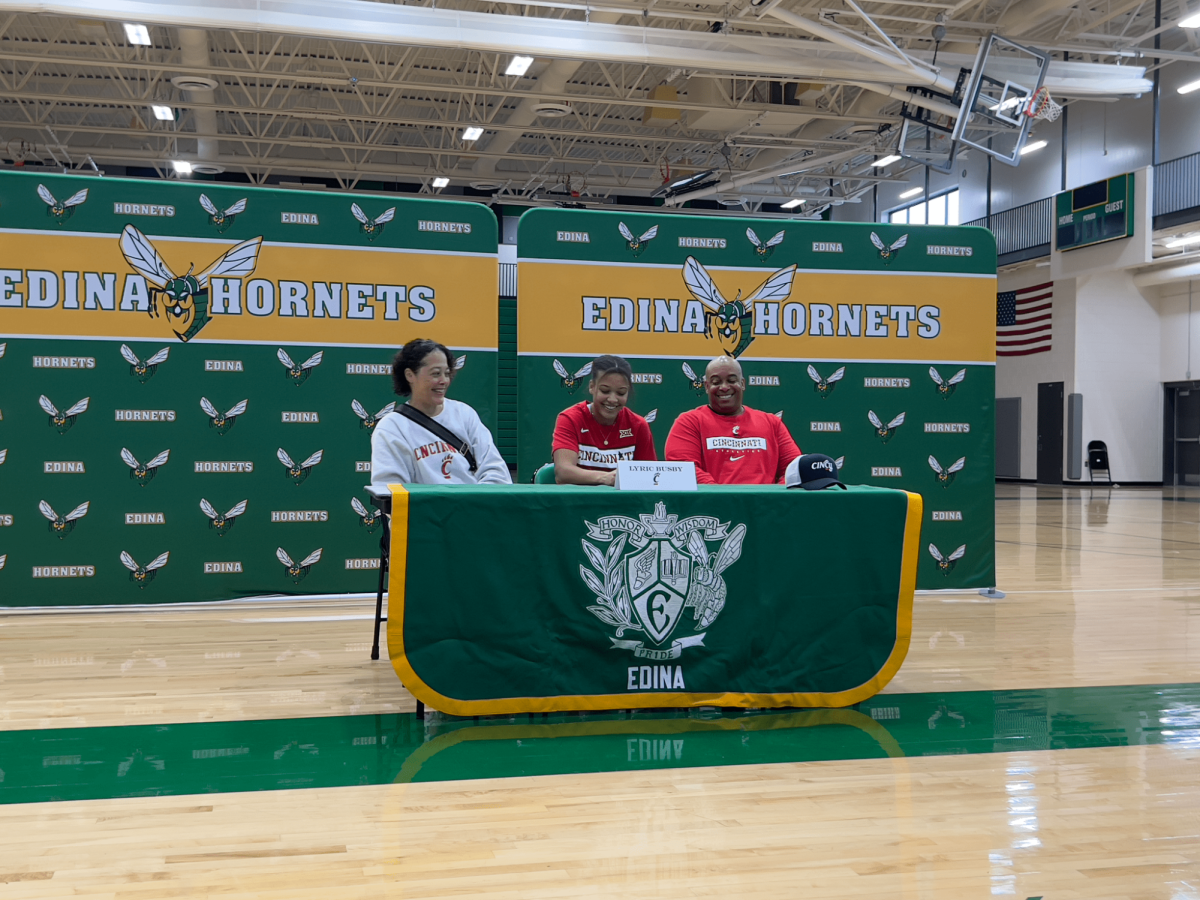 Senior Lyric Busby signs a letter of intent to University of Cincinnati with parents in support. 